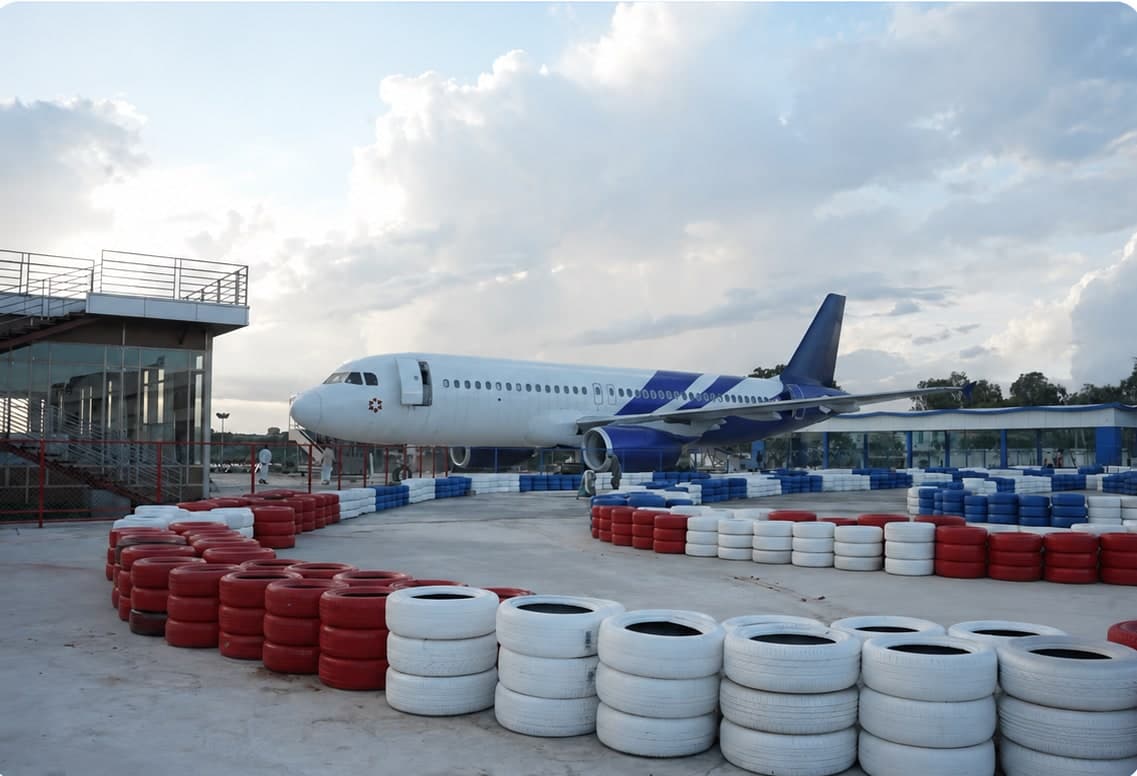 The Fly High aircraft office in Hyderabad: a blue-tailed Airbus A320 beside a go-karting track lined with tyres