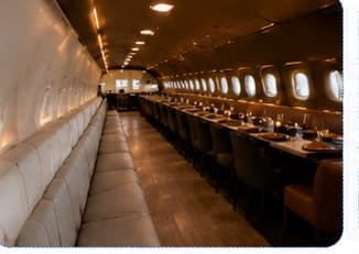 A row of set tables inside an aircraft restaurant cabin