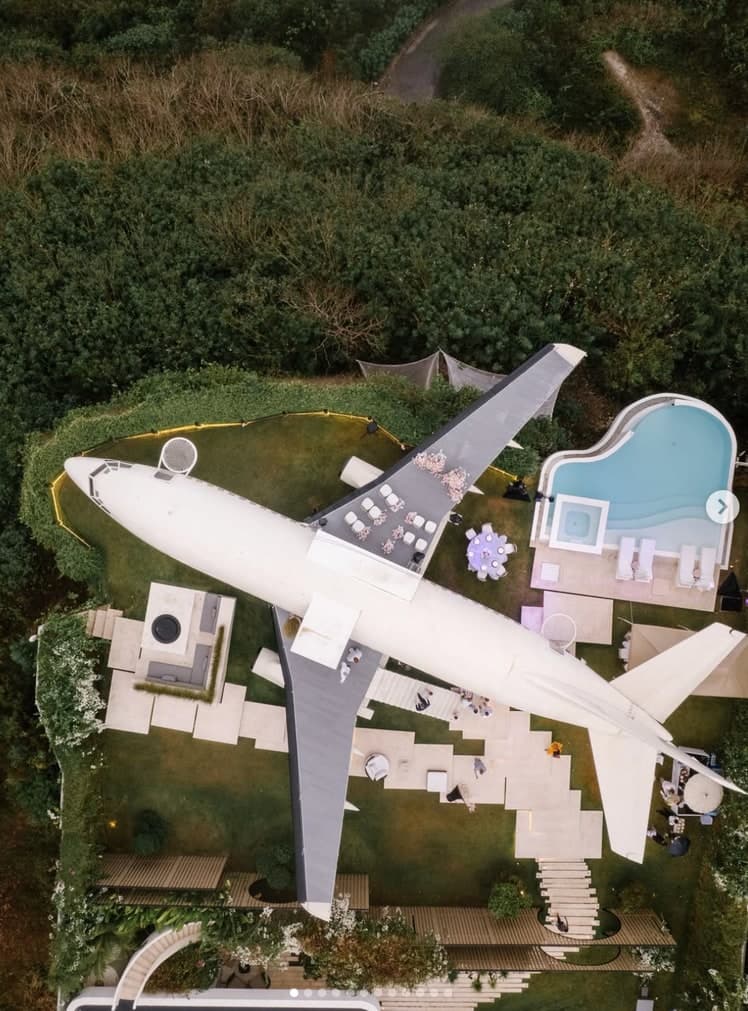 Aerial view of a jet airliner converted into a villa with a swimming pool built around it